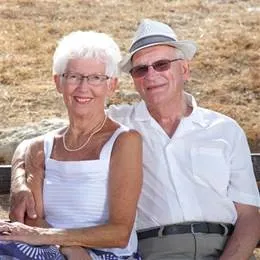 An elderly couple sit next to each other, smiling